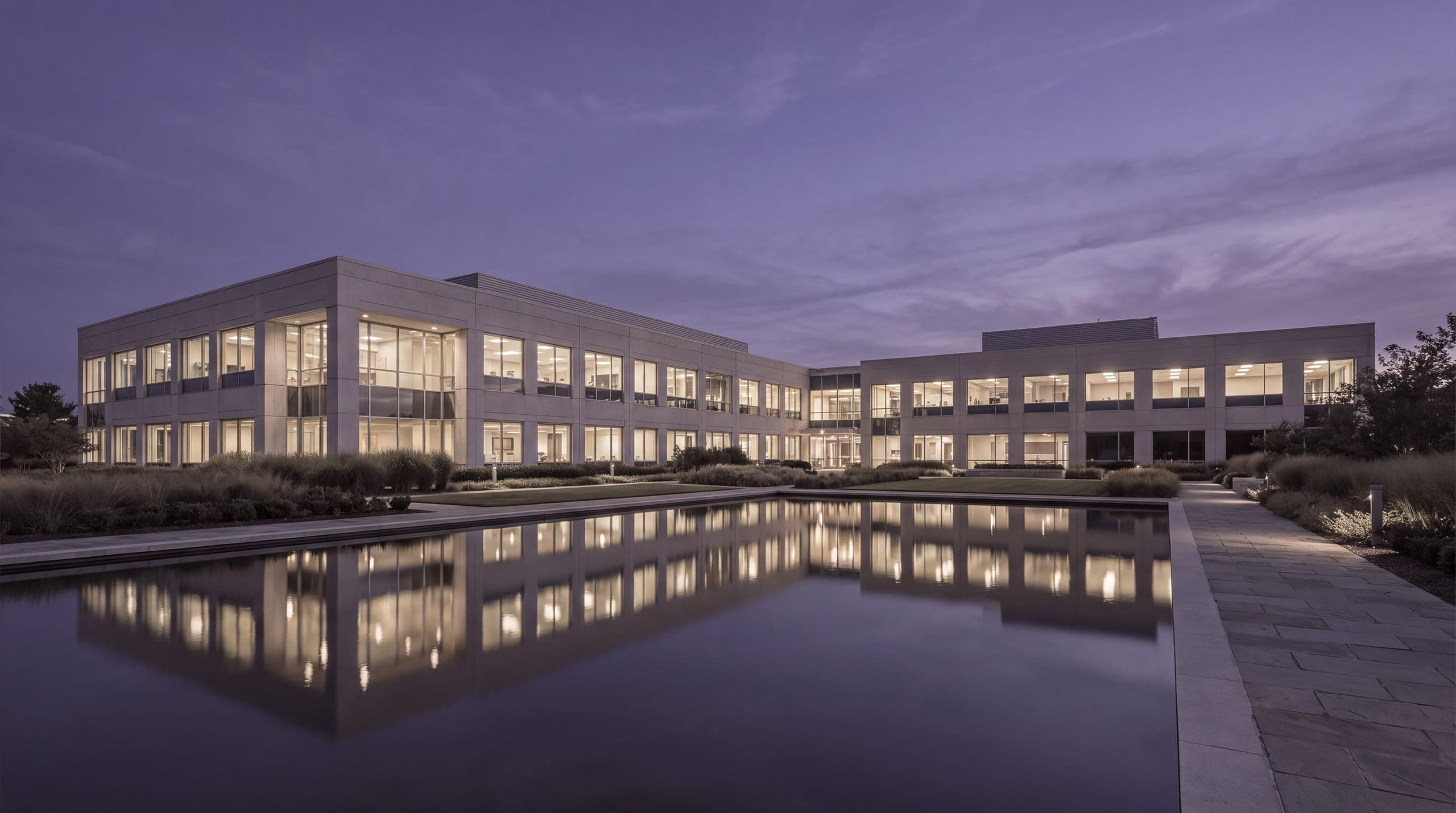 A low campus building reflected in still water at dusk