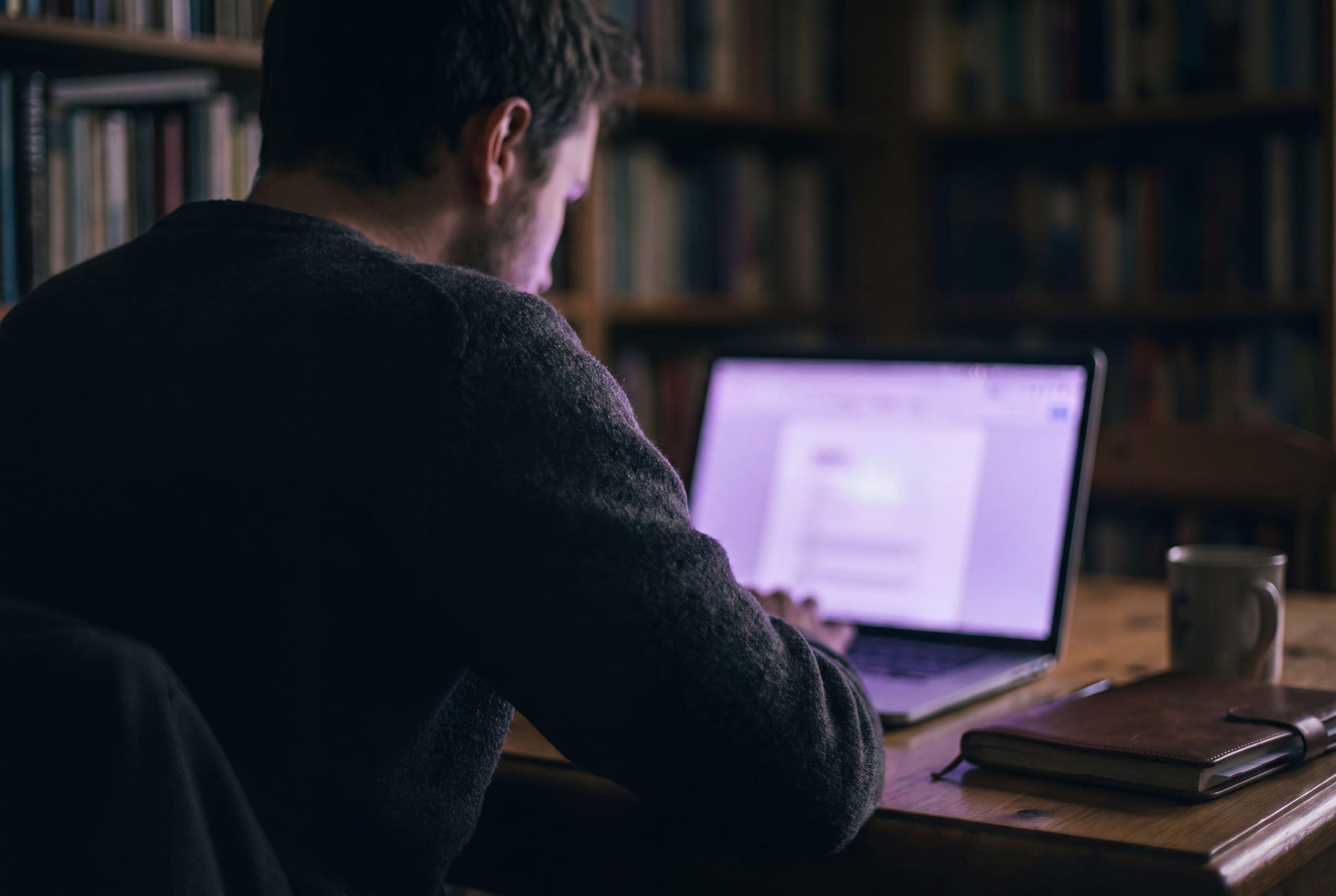 A person working at a laptop at a desk, seen from behind