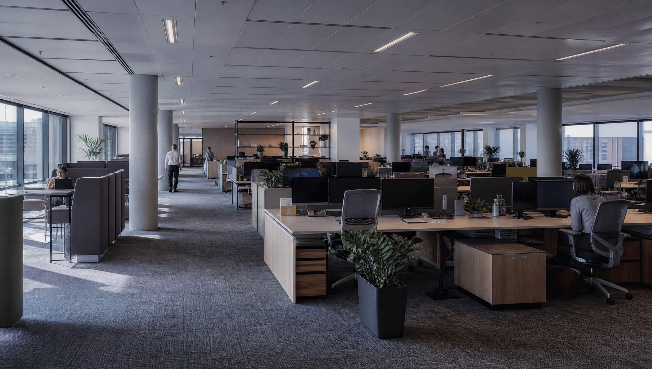 Open-plan office interior in daylight with people in the distance