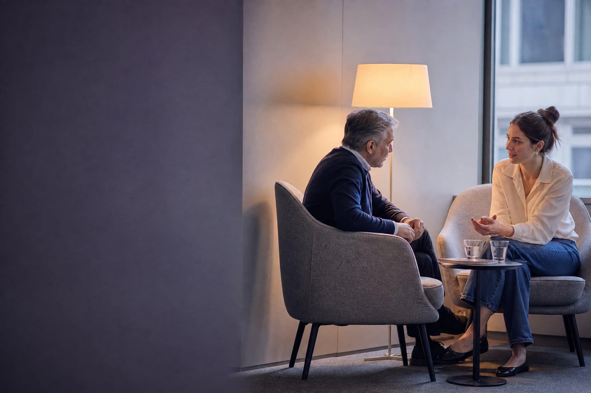 Two people talking in armchairs in a quiet corner